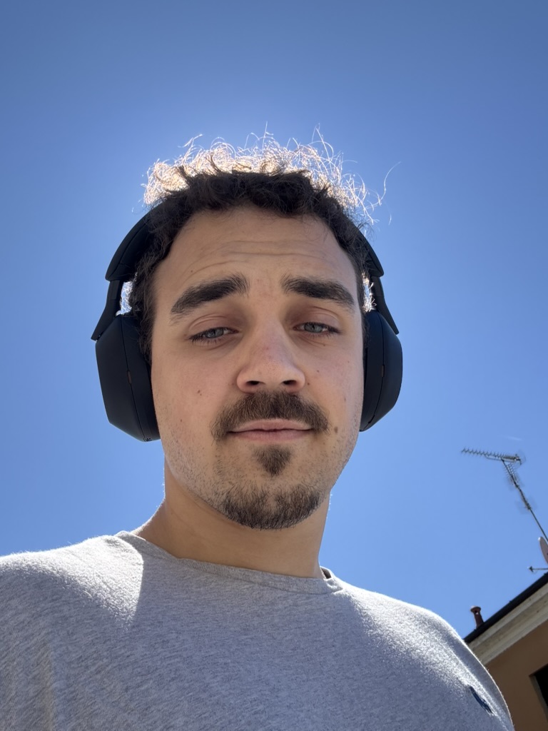 Francesco, headphones on, under a very blue sky